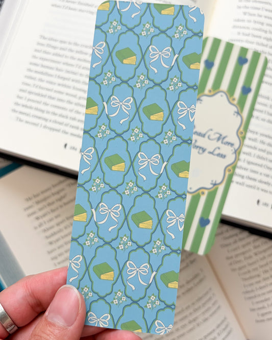 Hand holding a blue patterned bookmark over an open book
