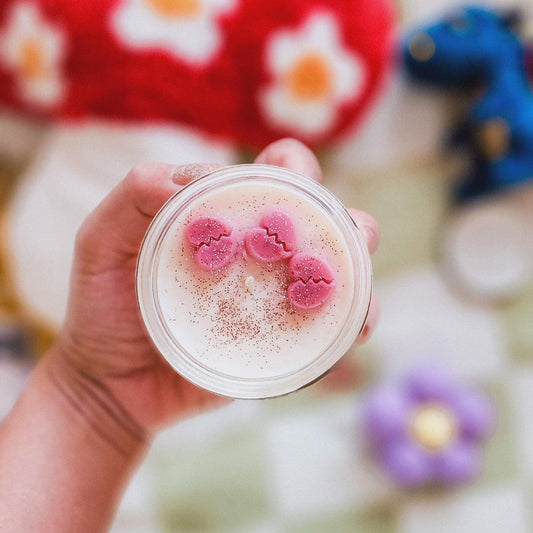 Hand holding a jar with pink heart-shaped wax melts and glitter, perfect for book lovers.