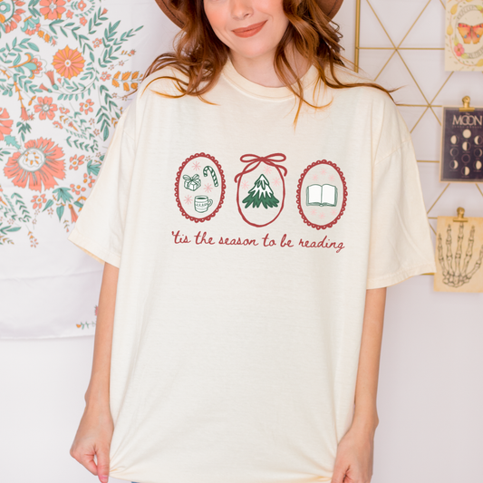 Woman wearing cream t-shirt with 'tis the season to be reading' and festive bookish graphics