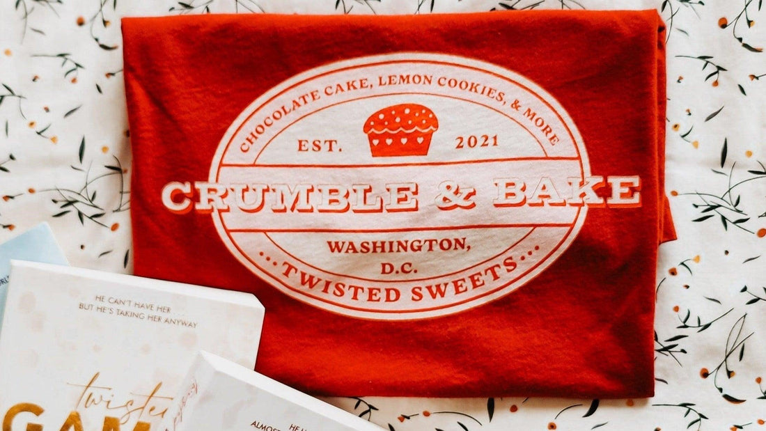 Red Crumble & Bake Twisted Sweets t-shirt with bakery logo on floral background, bookish merch