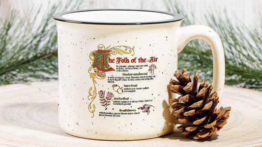 Speckled cream ceramic camp mug with The Folk of the Air quote, pinecone and greenery