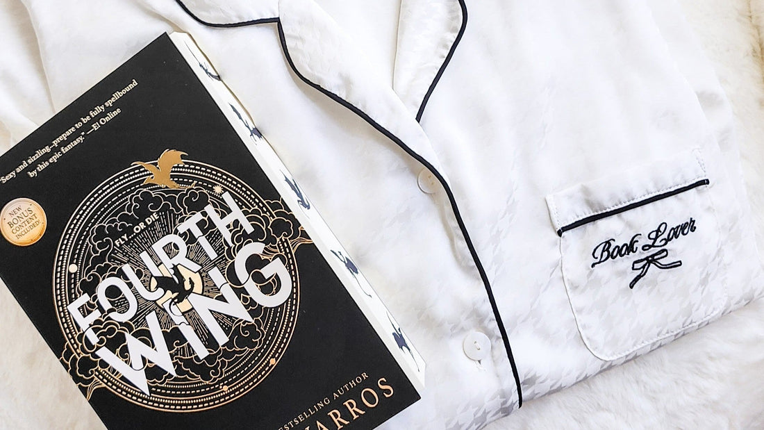 White 'Book Lover' pajamas with black trim beside 'Fourth Wing' book, perfect for bookish fans.
