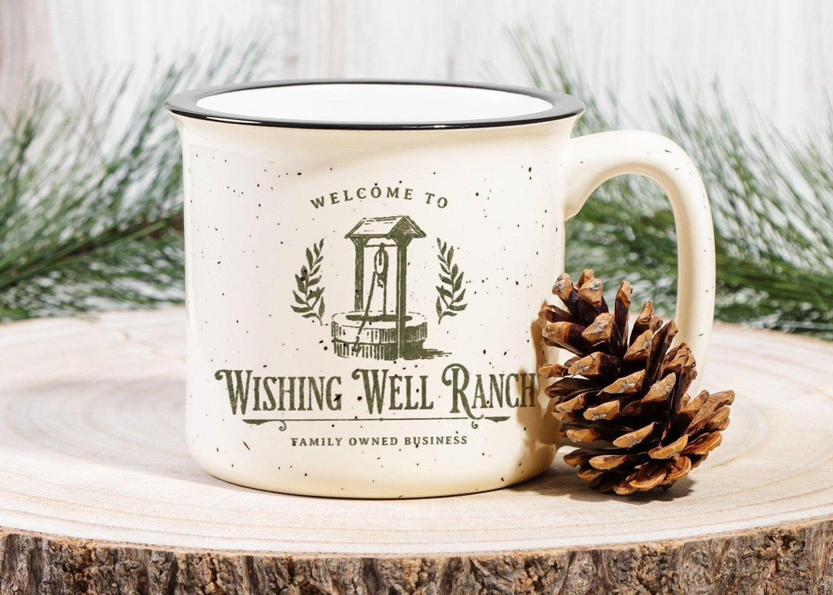 Cream ceramic mug with 'Welcome to Wishing Well Ranch' design, pinecone, pine branches