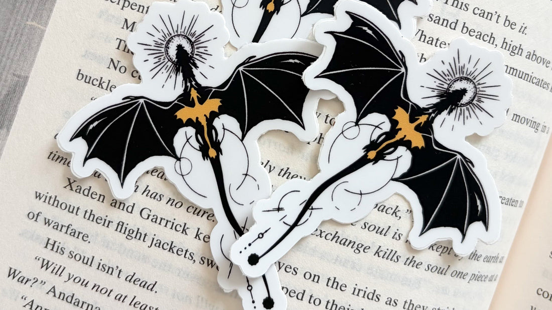 Bookish black dragon with gold accents vinyl sticker on open book page