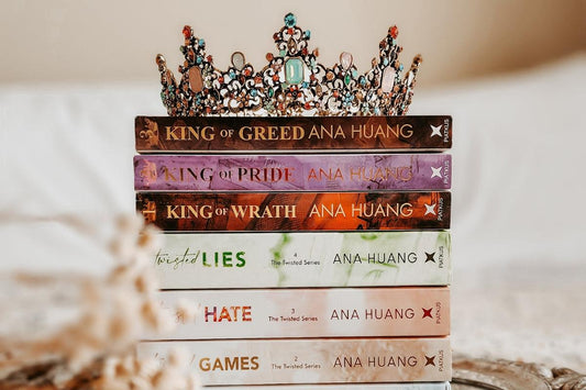 Stack of Ana Huang romance novels with jeweled crown on top, fantasy book aesthetic