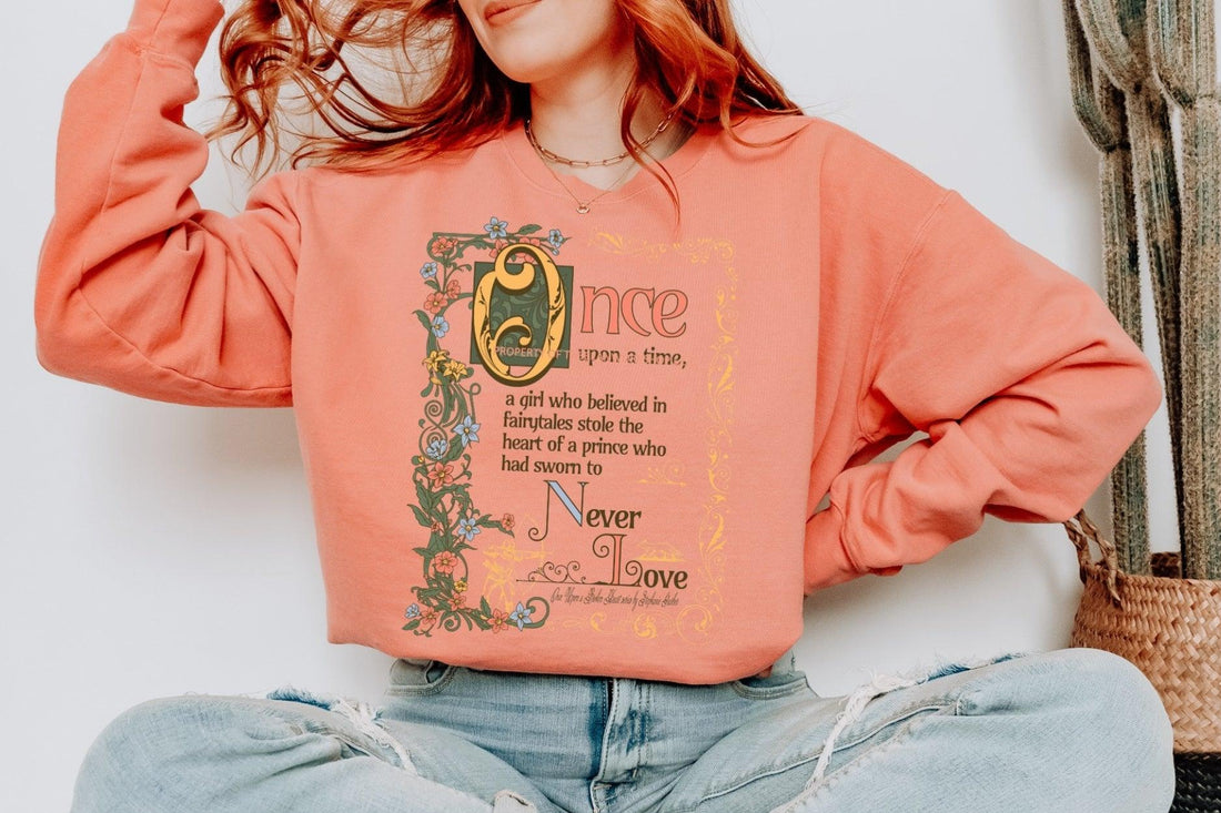 Bookish quote sweatshirt in coral with floral medieval script, worn by woman in casual setting
