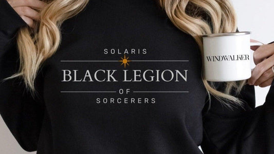 Person wearing Black Legion of Sorcerers Solaris sweatshirt holding Windwalker mug