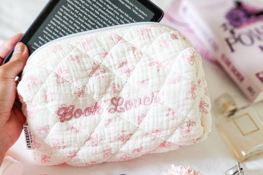 Quilted pouch with pink bows and 'Book Lover' embroidery, held with an e-reader