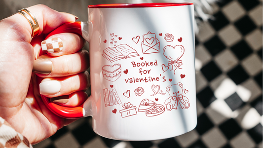 White mug with red rim featuring 'Booked for valentine's' and romantic bookish illustrations