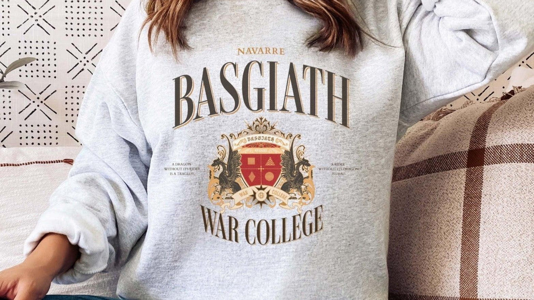 Person wearing a gray Basgiath War College sweatshirt with crest and fantasy bookish design