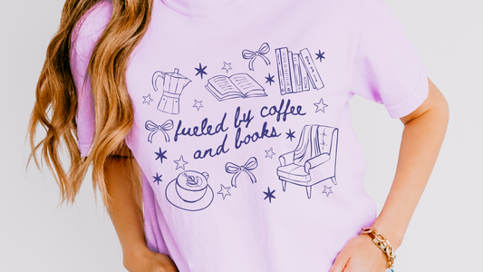 Lavender tee with 'fueled by coffee and books' and book, coffee, chair illustrations