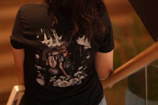 Woman wearing a black book-themed graphic tee with fantasy illustration and floral accents