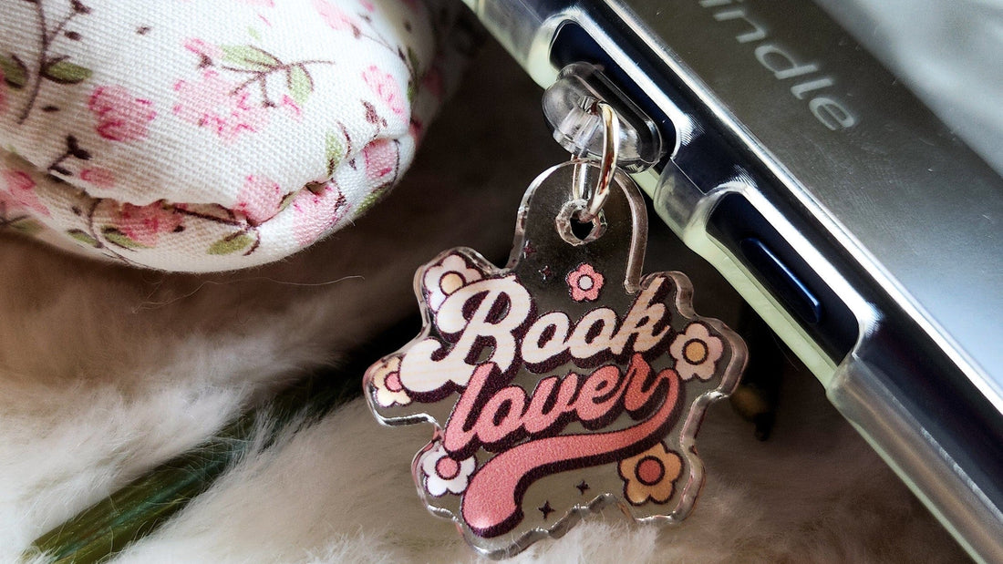 Book lover acrylic charm attached to Kindle with floral fabric and cozy background