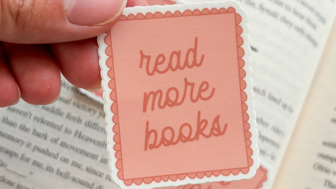 Pink read more books sticker with scalloped border held above an open book