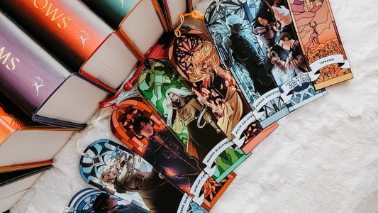 Colorful fantasy book-inspired bookmarks with character art beside stacked hardcover books