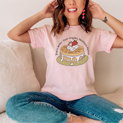 Woman wearing a pink graphic tee with waffle, whipped cream, and book quote illustration