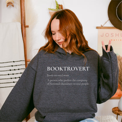 Woman wearing a dark gray hoodie with 'Booktrovert' definition, cozy bookish apparel