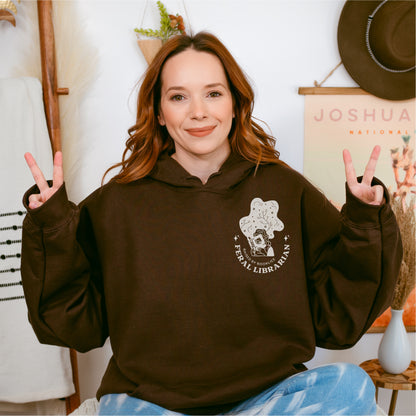 Woman wearing dark chocolate brown Feral Librarian hoodie with bookish graphic print