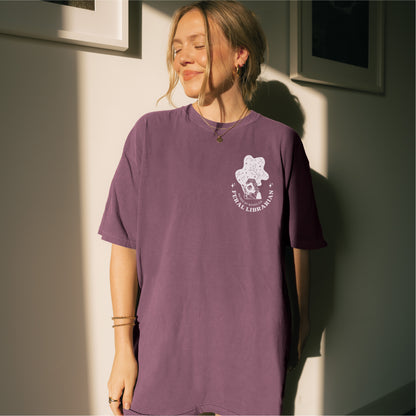 Woman wearing purple Feral Librarian t-shirt with graphic and text on chest, bookish apparel