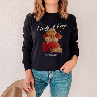 Black long sleeve tee with illustrated girl, book, and 'I hate it here' text, bookish apparel