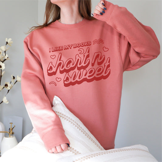 Pink book lover sweatshirt with 'I Like My Books Short n' Sweet' text and heart graphics