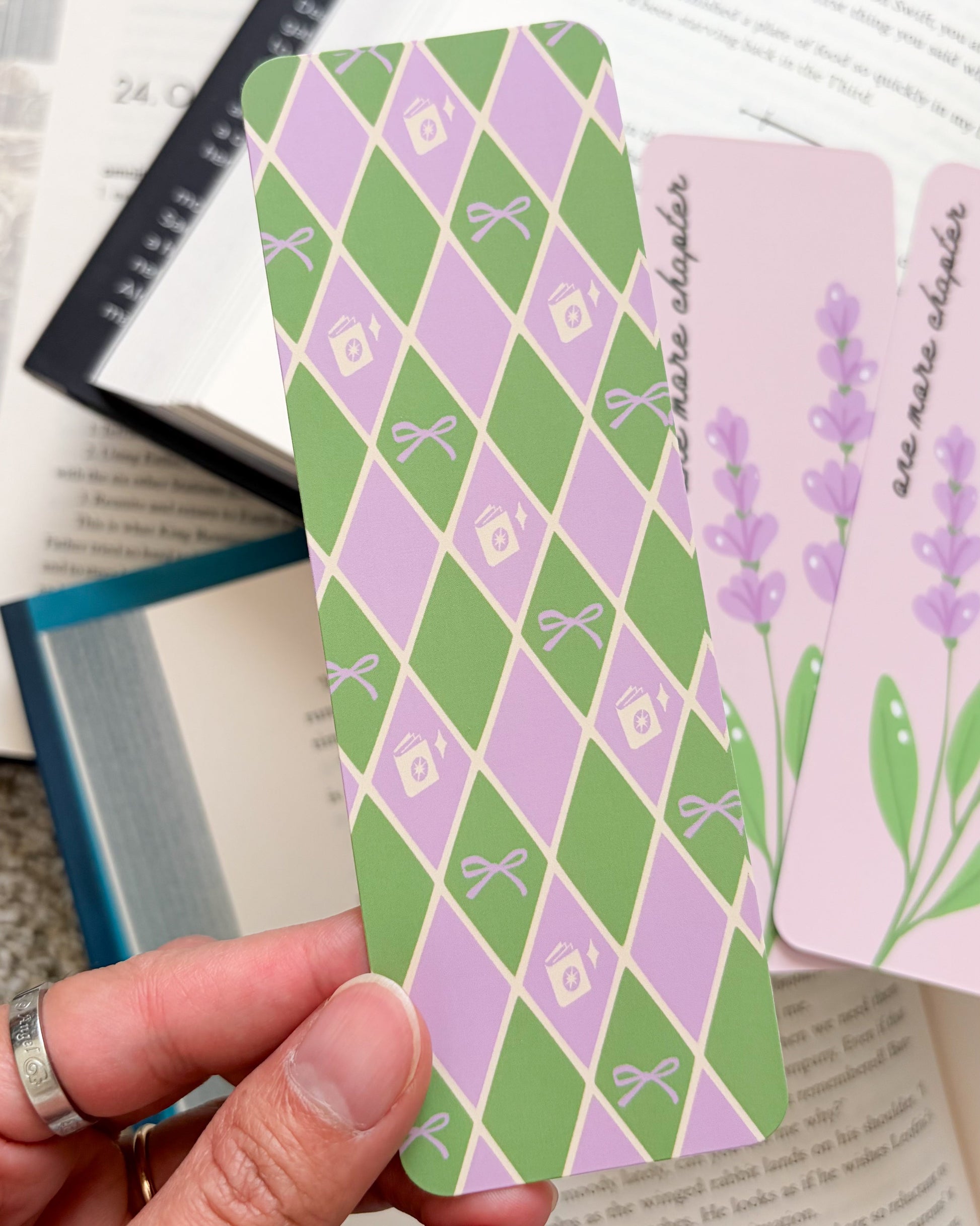 Hand holding a green and purple patterned card over an open book