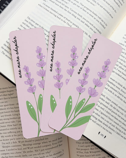 Three pink bookmarks with lavender designs on an open book.