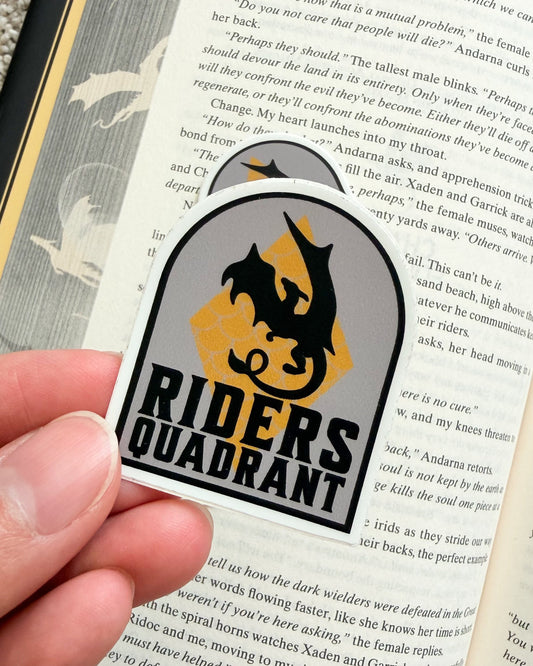 Sticker with 'Riders Quadrant' logo held over a book