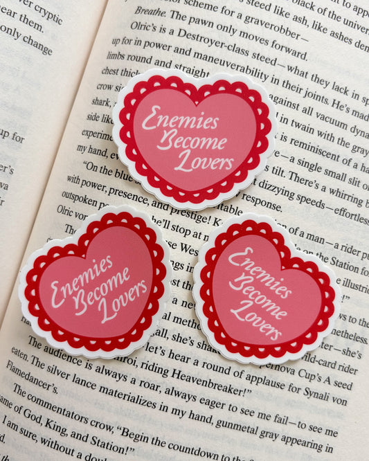 Heart-shaped stickers with 'Enemies Become Lovers' text on a book page