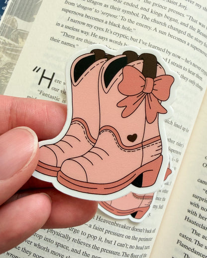 Pink cartoon boot with a bow held over an open book