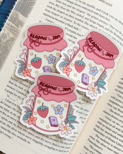 Sticker of a jar labeled 'Reading is my Jam' on an open book
