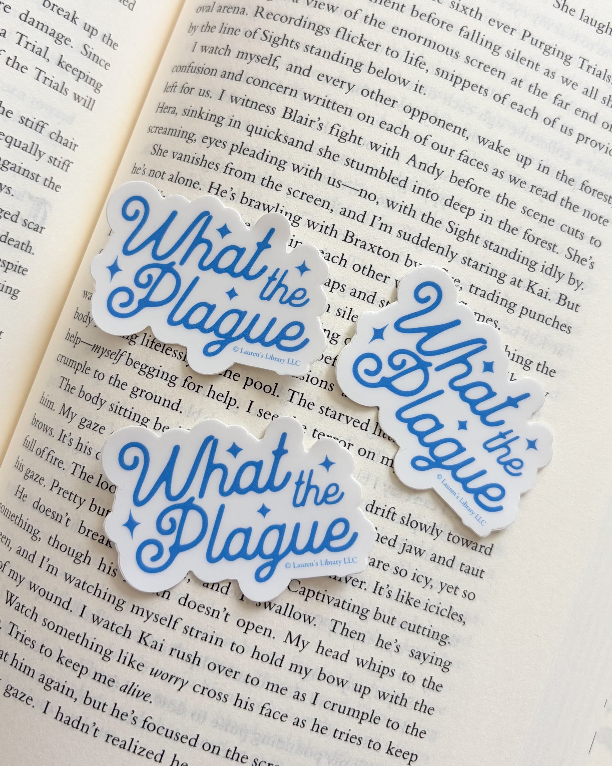 Three 'What the Plague' stickers on an open book