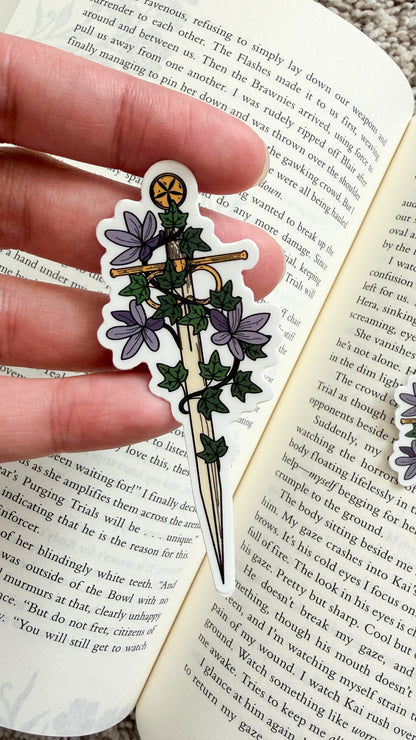 Decorative sticker with floral design held over an open book