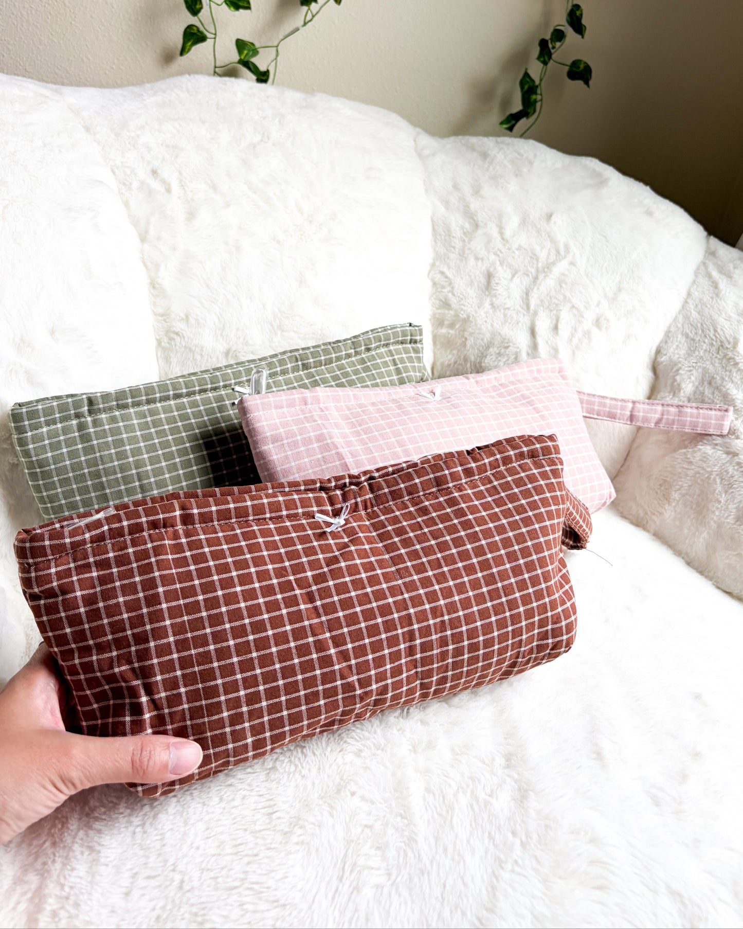 Terracotta quilted pouch held in hand with sage green and pink pouches in background