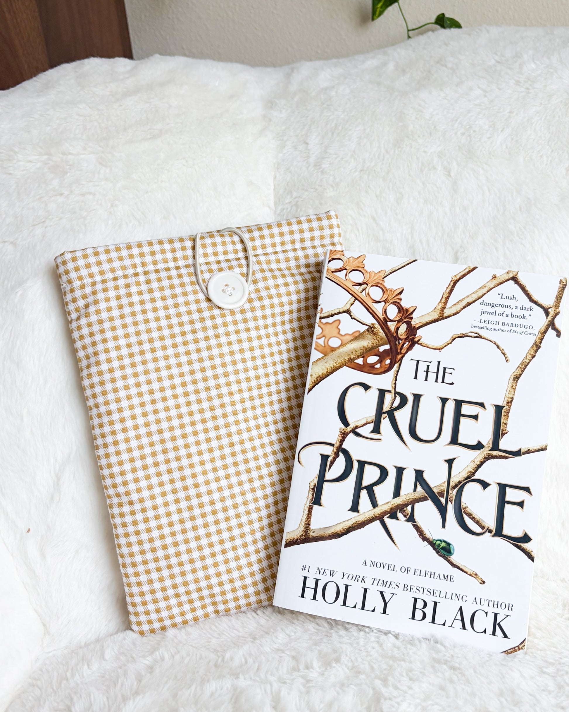 Golden gingham book sleeve beside The Cruel Prince book
