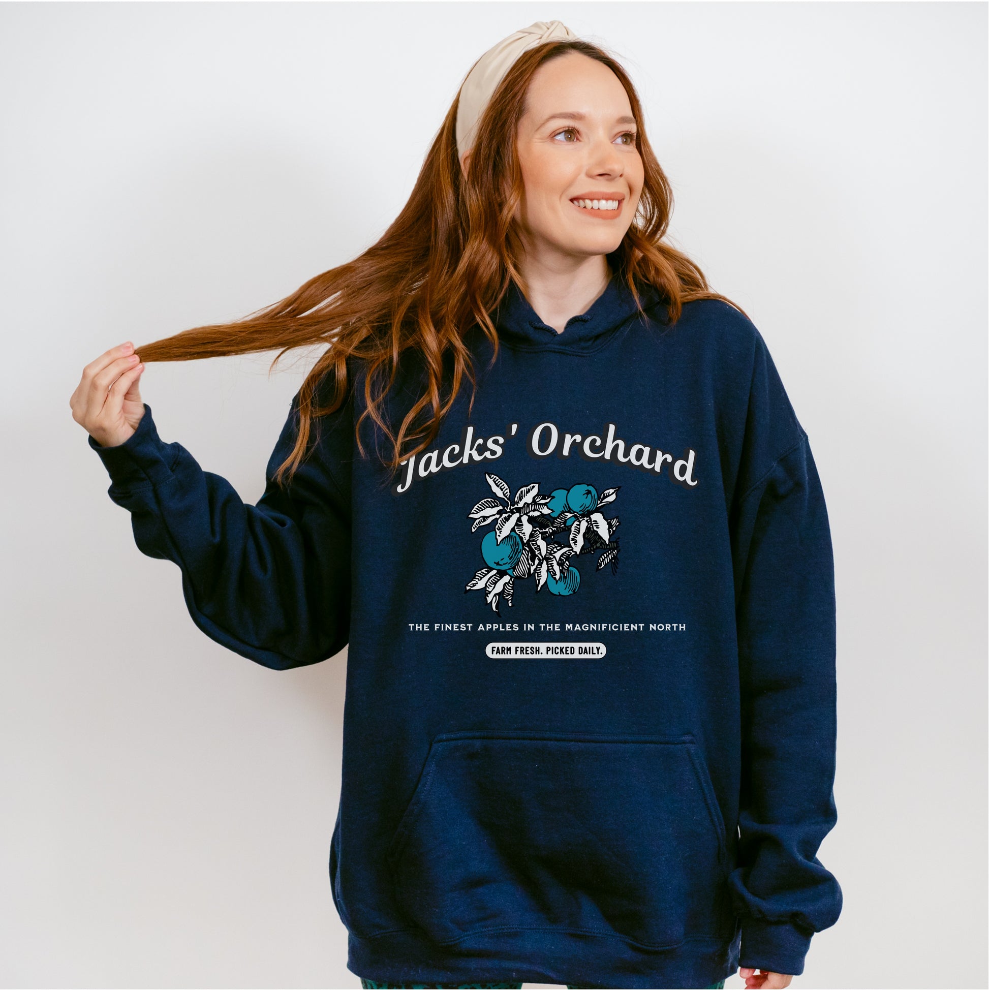 Woman wearing a navy Jacks' Orchard hoodie with illustrated apple and leaf graphic