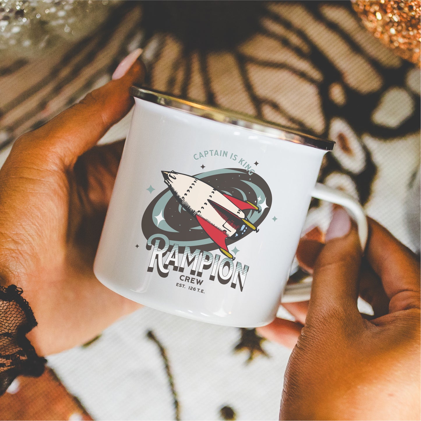 White enamel mug featuring illustrated spaceship, Rampion Crew design, held in hands