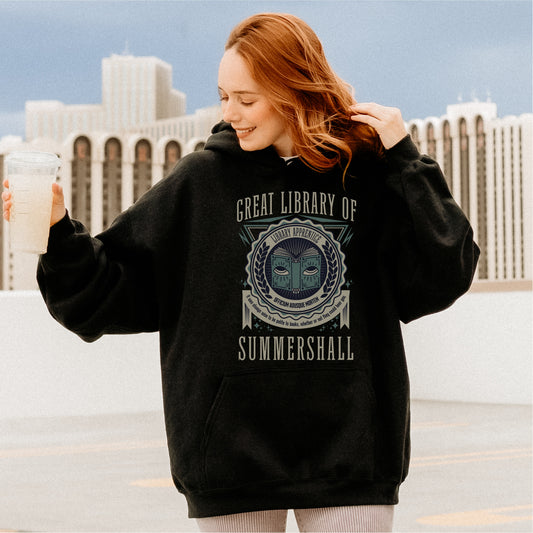 Woman wearing black Great Library of Summershall hoodie with bookish graphic, rooftop background