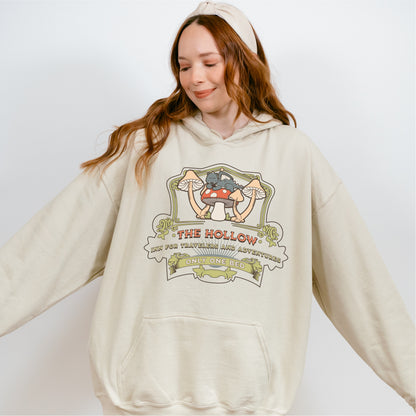 Woman wearing a beige hoodie with whimsical bookish artwork and mushroom graphic print.