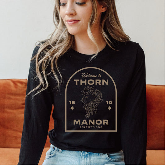 Woman wearing black Thorn Manor long sleeve tee with fantasy cat design and text graphic