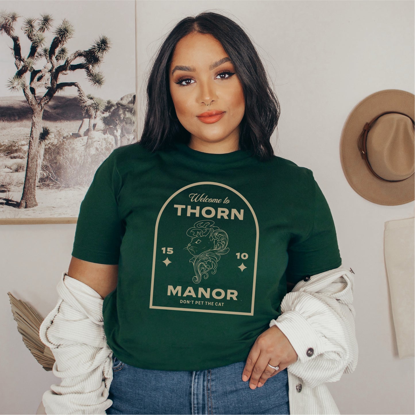 Woman wearing a green Thorn Manor graphic tee shirt with vintage-inspired bookish design