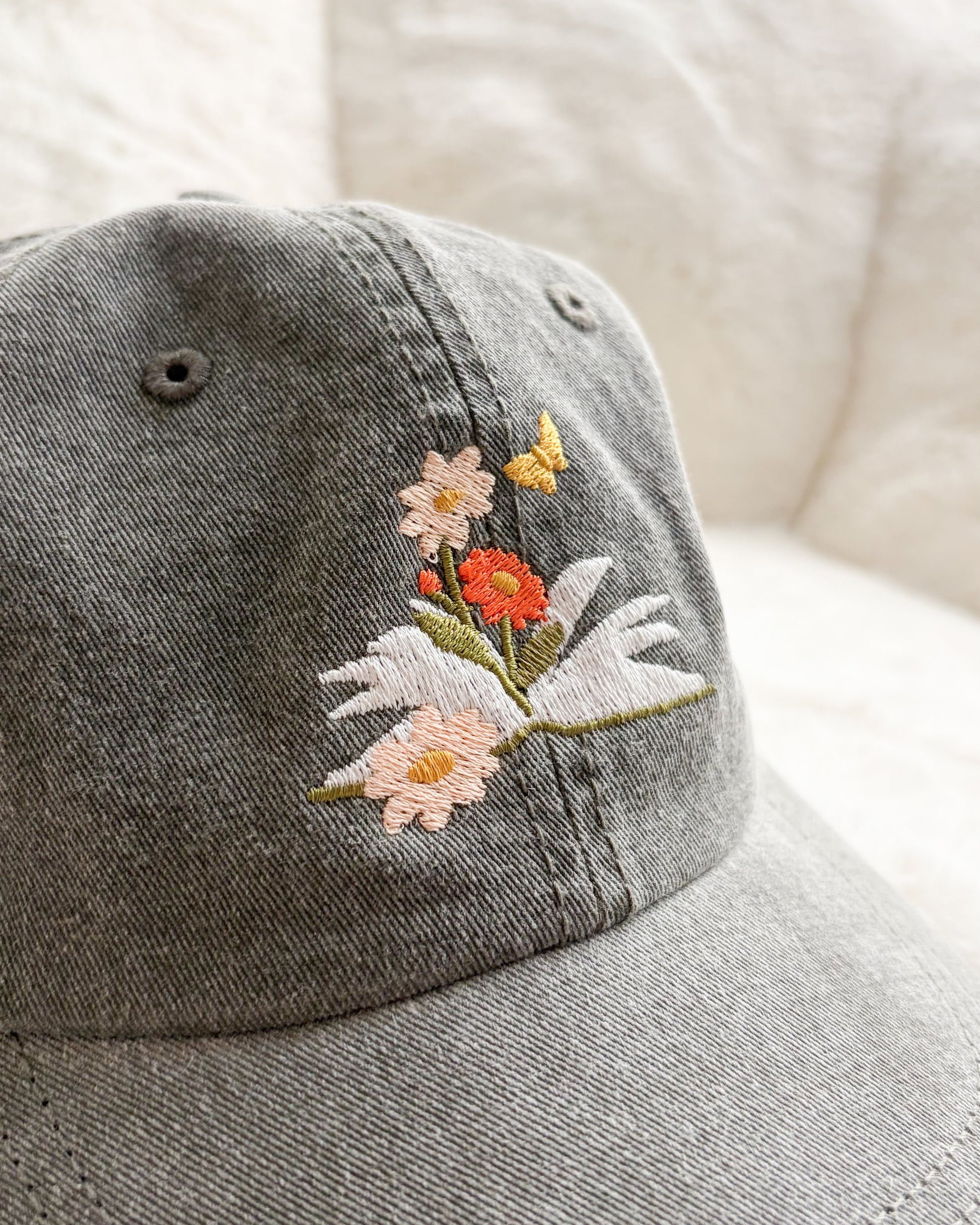 Grey cap with embroidered flowers, open book, and butterfly design, bookish merchandise