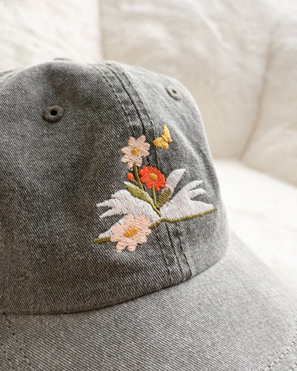 Grey cap with embroidered flowers, open book, and butterfly design, bookish merchandise
