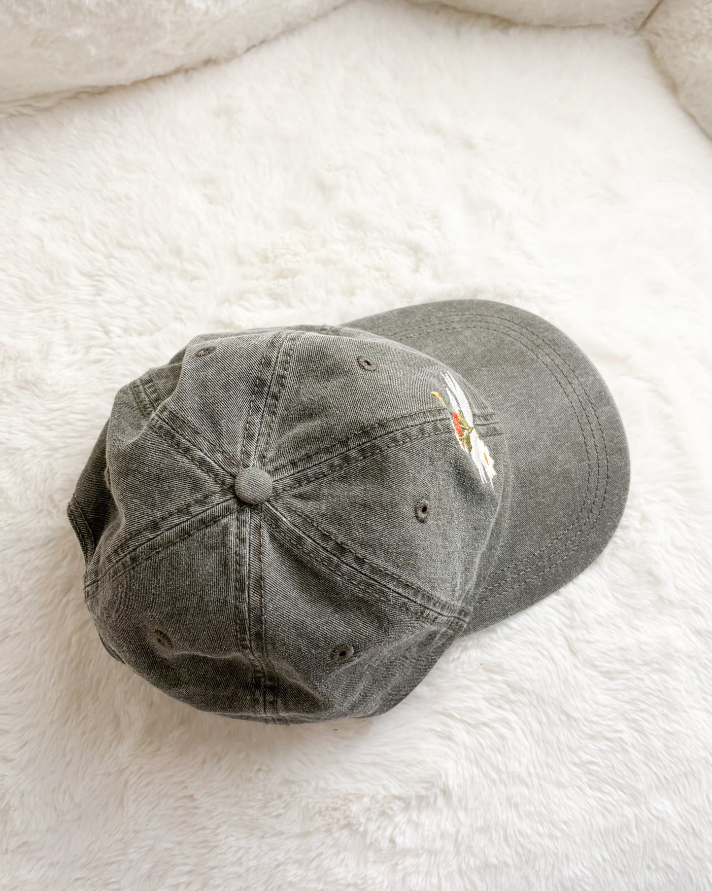 Grey embroidered baseball cap on soft white fabric background