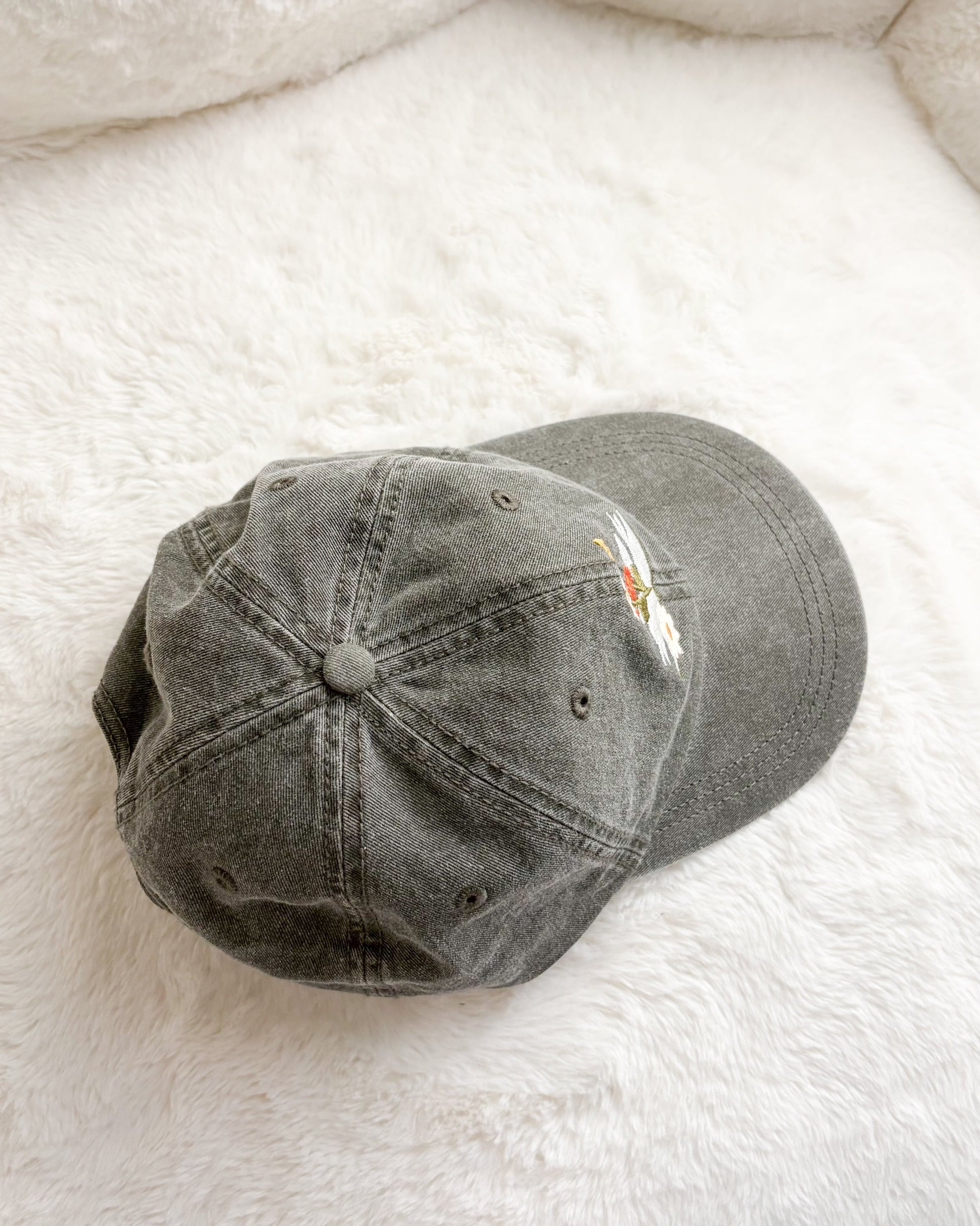 Grey embroidered baseball cap on soft white fabric background