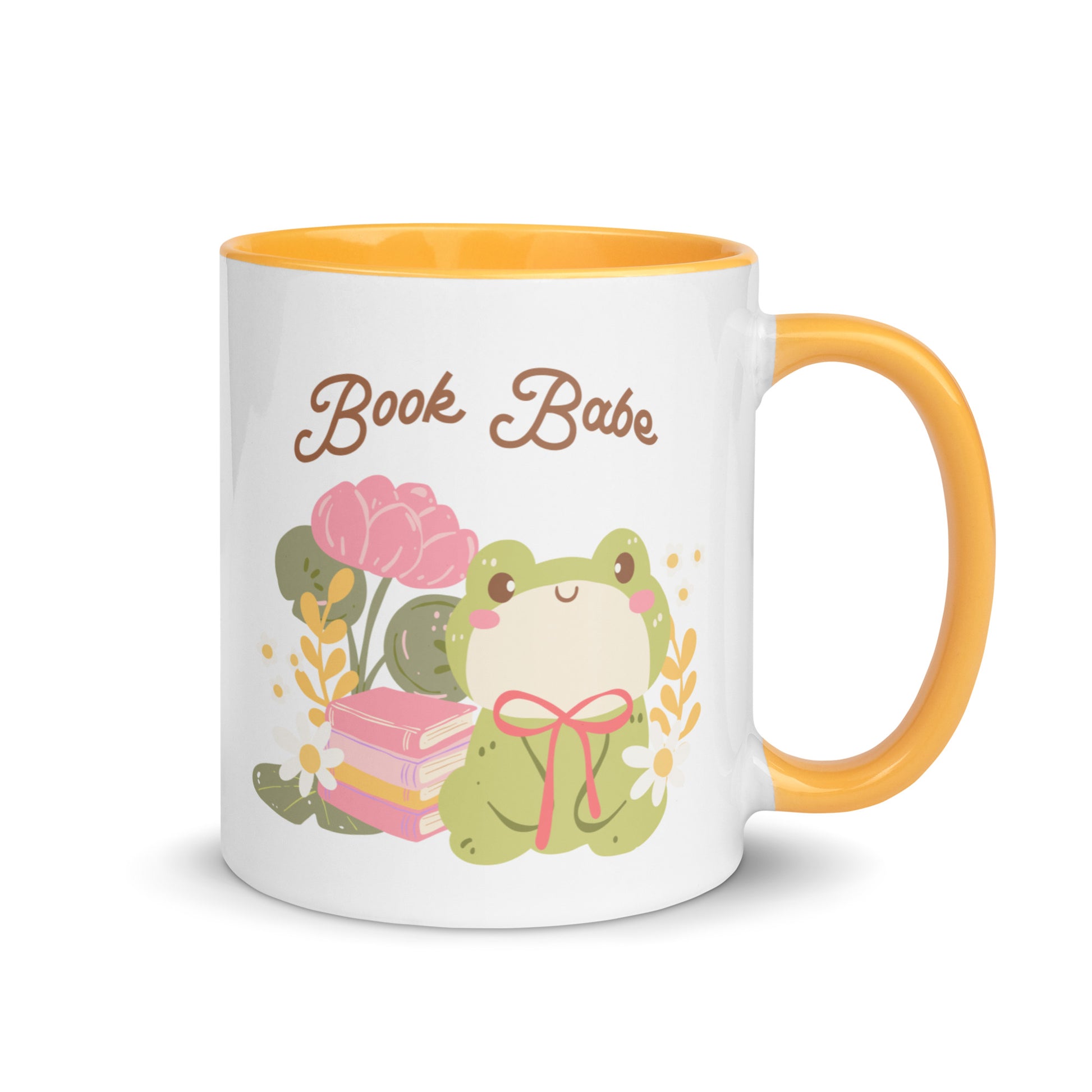 White ceramic mug with yellow handle, featuring a cute frog, flowers, books, and 'Book Babe' text.