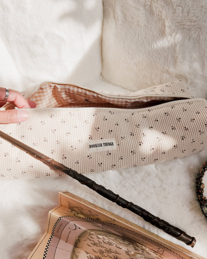 Striped corduroy travel bag with 'Bookish Things' label, magic wand, and parchment map