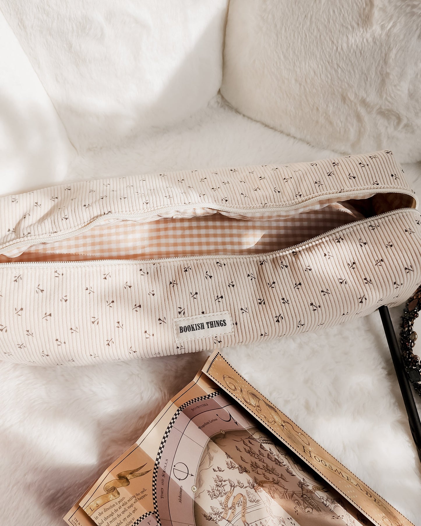 Beige corduroy travel bag with floral print and 'Bookish Things' label on soft white fabric