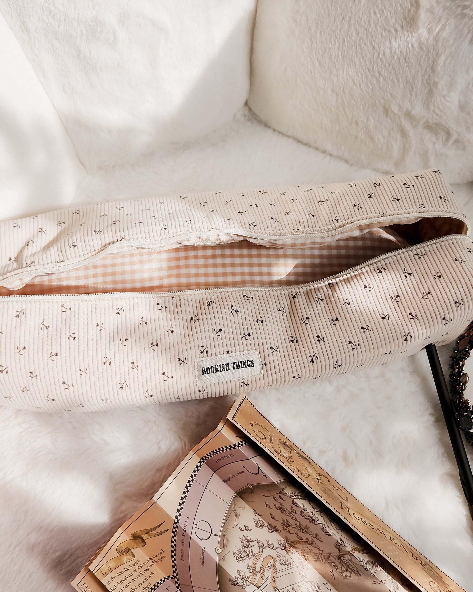 Beige corduroy travel bag with floral print and 'Bookish Things' label on soft white fabric