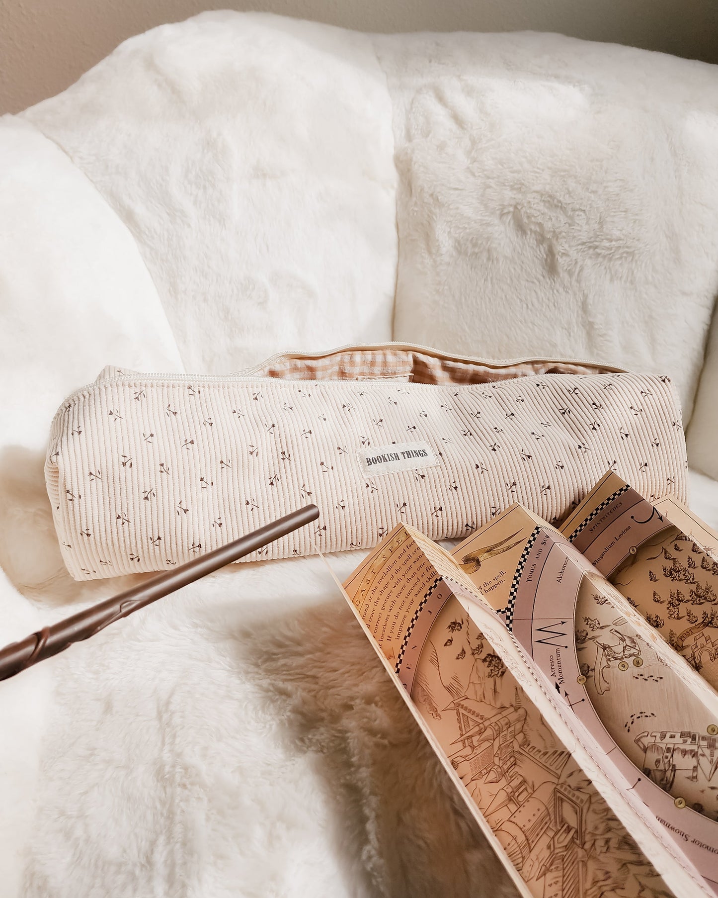 Bookish Things corduroy travel bag with map and wand on white faux fur chair